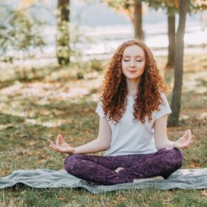 Woman meditating in a serene park during springtime, fostering relaxation and mental wellness.
