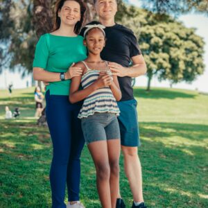 Smiling family standing together in a sunny park, symbolizing happiness and togetherness.