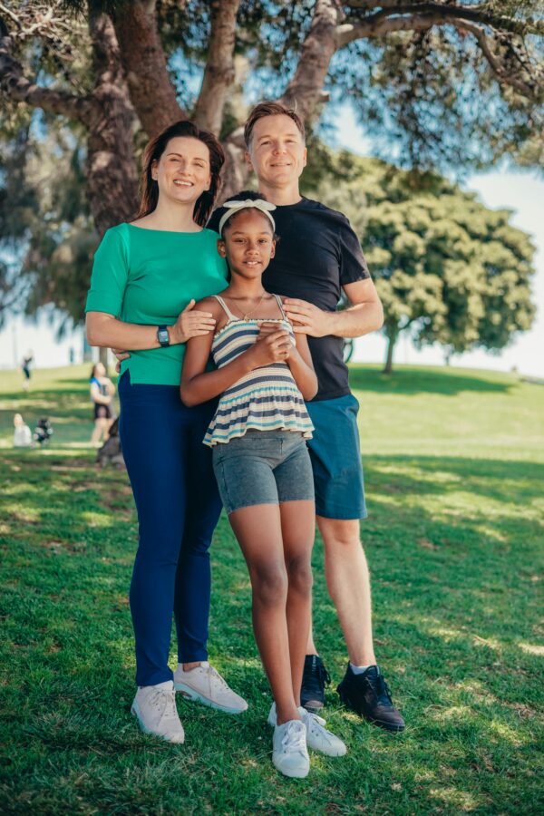 Smiling family standing together in a sunny park, symbolizing happiness and togetherness.