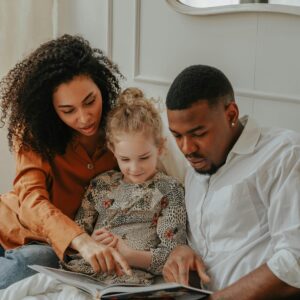 A happy multi-ethnic family reading a book together indoors, showcasing love and bonding.