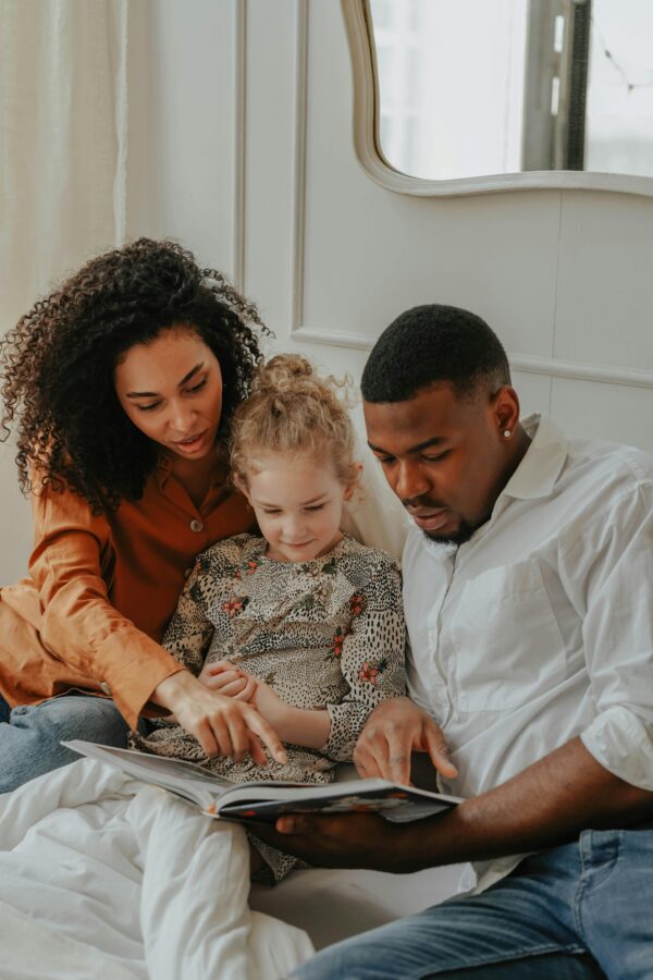 A happy multi-ethnic family reading a book together indoors, showcasing love and bonding.